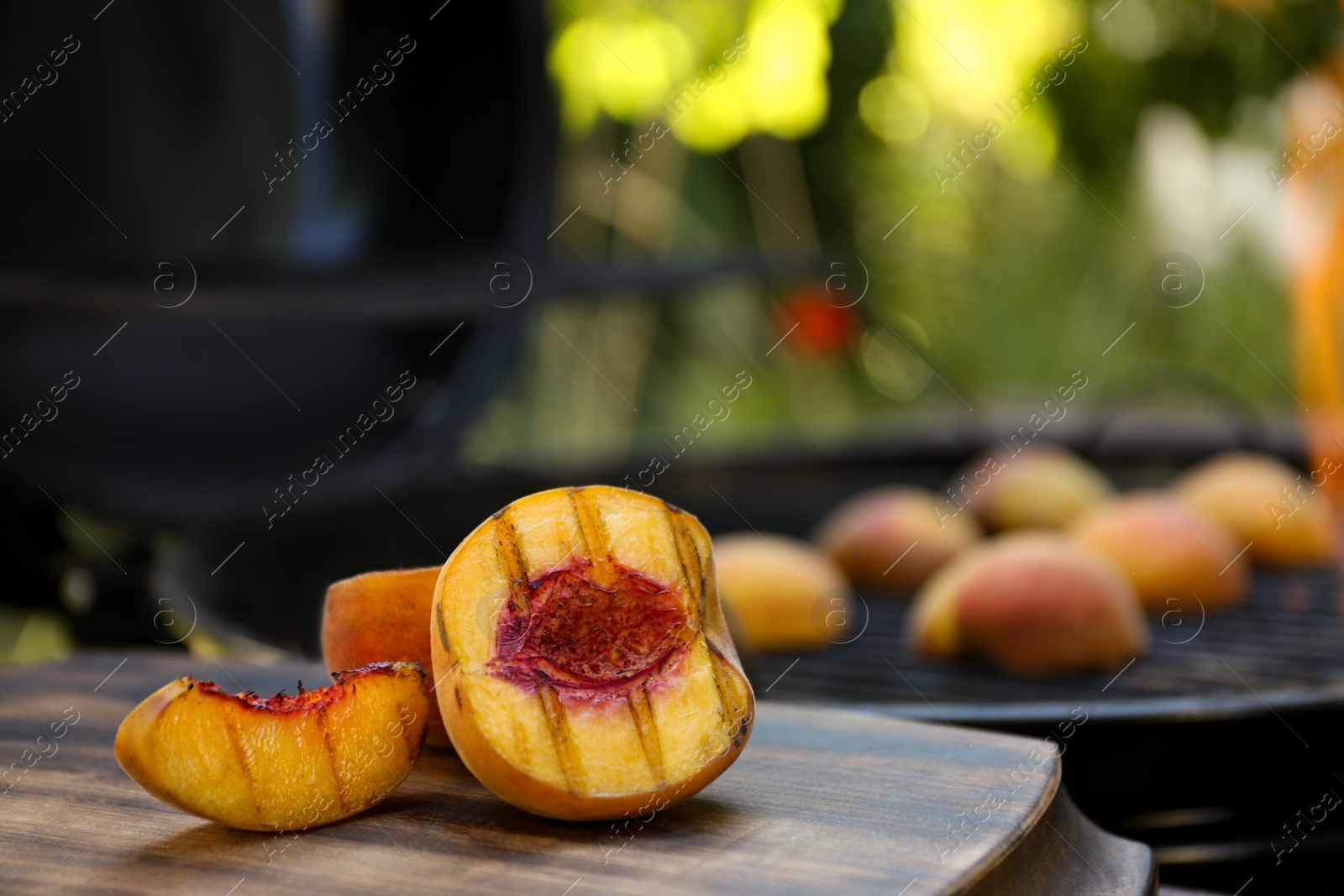 Photo of Cut delicious grilled peach on wooden table outdoors, closeup