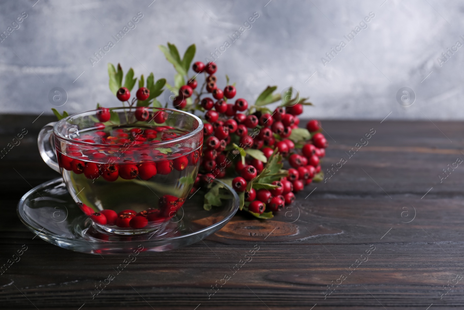 Photo of Cup of delicious immunity boosting tea with hawthorn on wooden table. Space for text