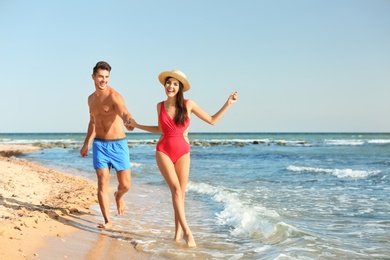 Happy young couple having fun at beach on sunny day