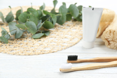 Photo of Bamboo toothbrushes on white wooden table. Space for text