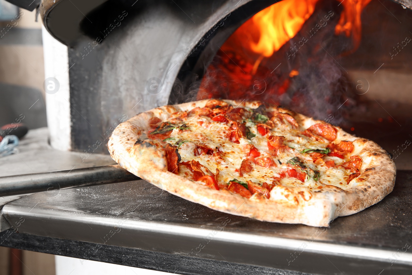 Photo of Taking out tasty pizza from oven in restaurant kitchen