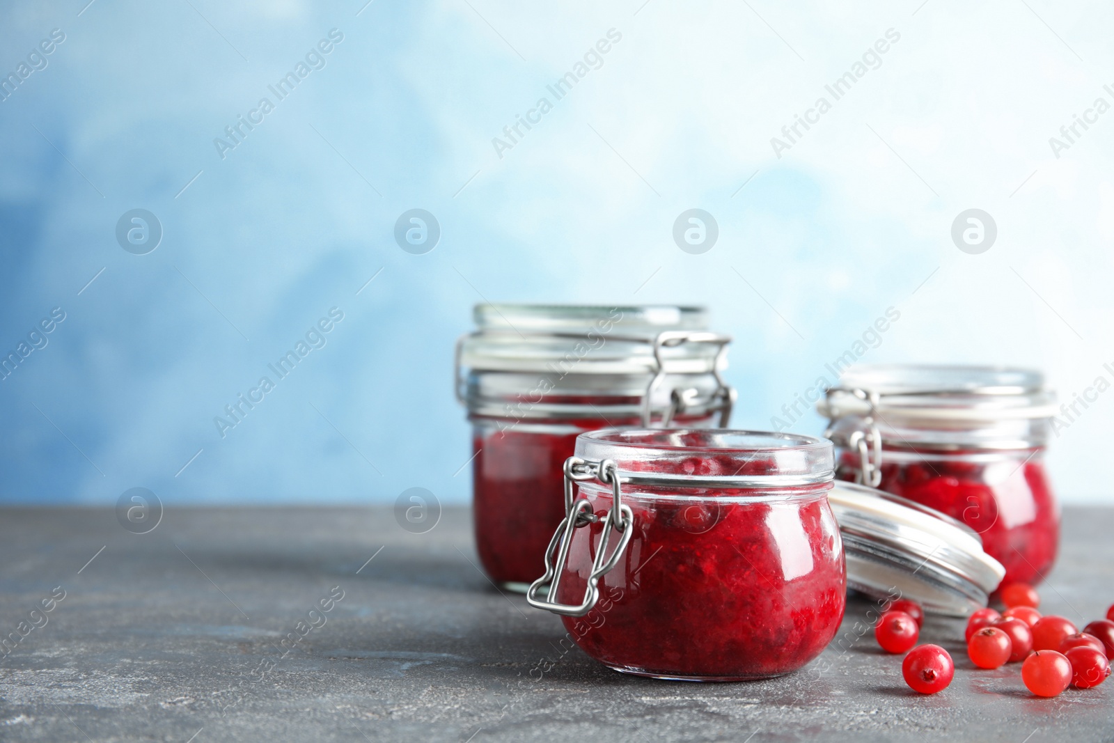 Photo of Glass jars with tasty cranberry sauce on table. Space for text