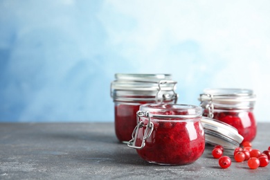 Glass jars with tasty cranberry sauce on table. Space for text