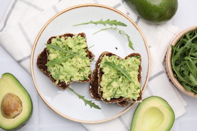 Photo of Delicious sandwiches with guacamole, arugula and avocados on table, flat lay