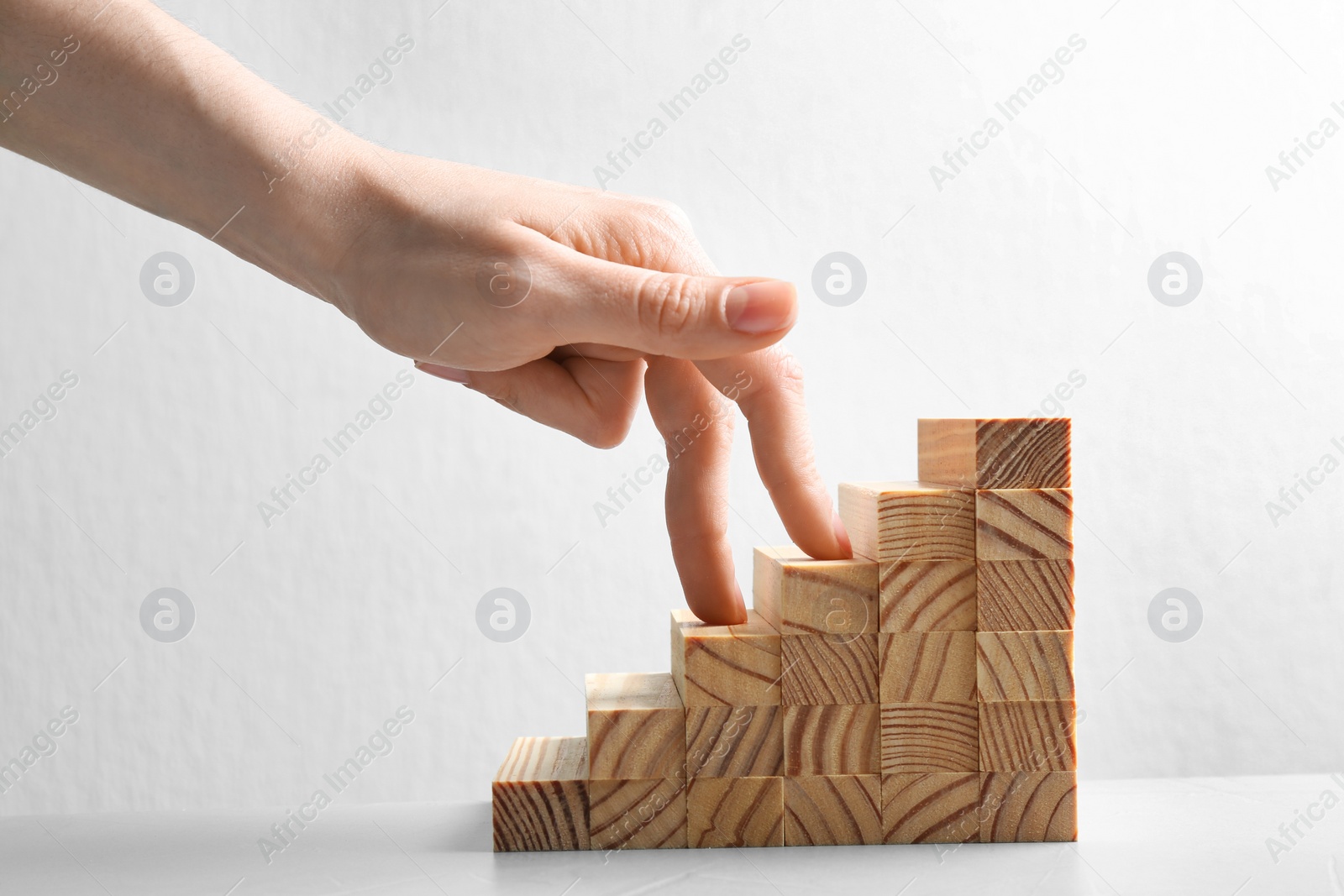 Photo of Woman and staircase made with wooden cubes on white background, closeup. Career promotion concept