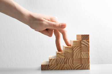Woman and staircase made with wooden cubes on white background, closeup. Career promotion concept