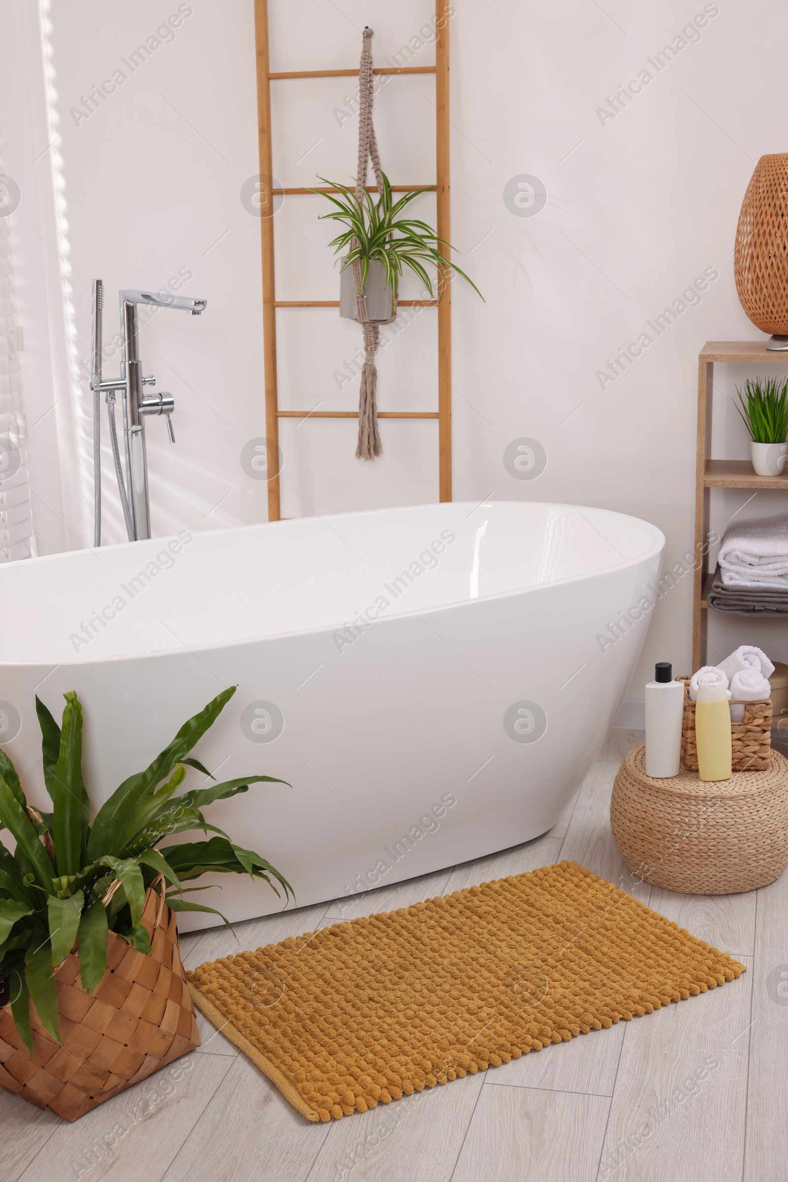 Photo of Stylish bathroom interior with soft bath mat and tub