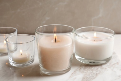 Burning candles in glasses on marble table