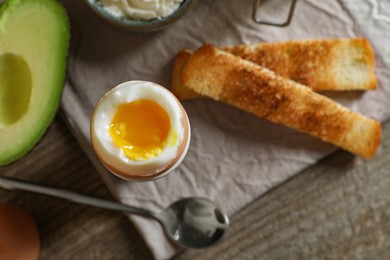 Photo of Soft boiled egg served for breakfast on wooden table, flat lay