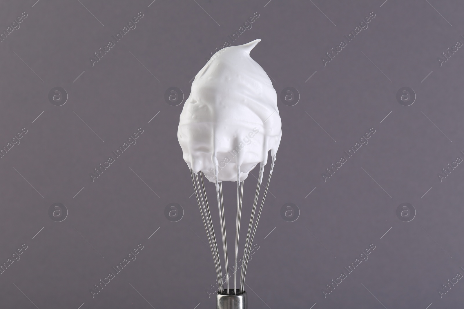 Photo of Whisk with whipped cream on grey background