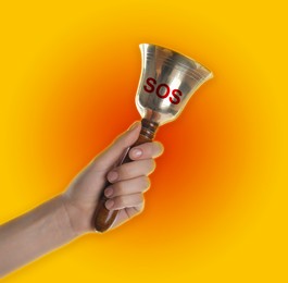 Woman ringing bell with abbreviation SOS on color background, closeup