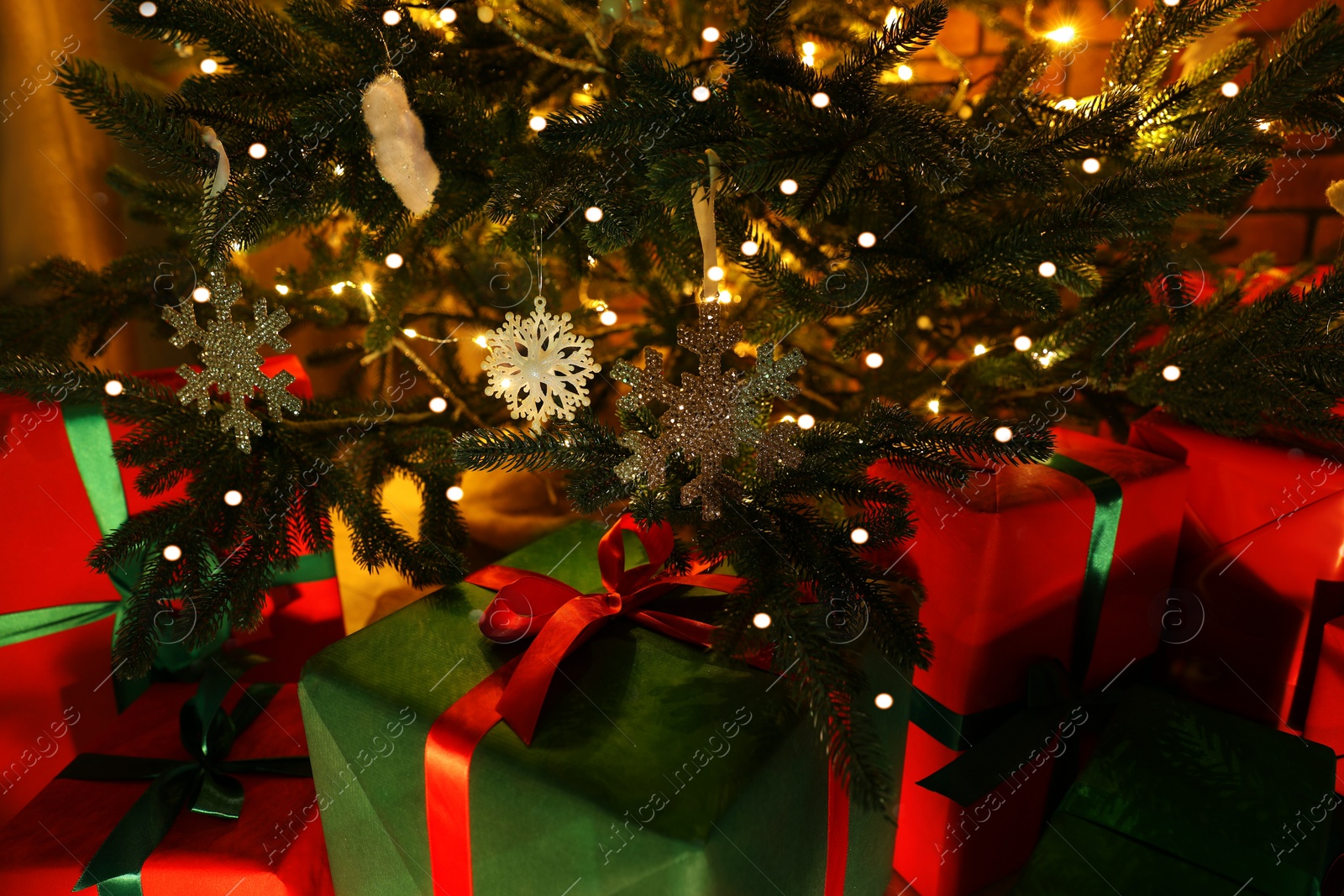 Photo of Beautifully wrapped gift boxes under Christmas tree indoors, closeup