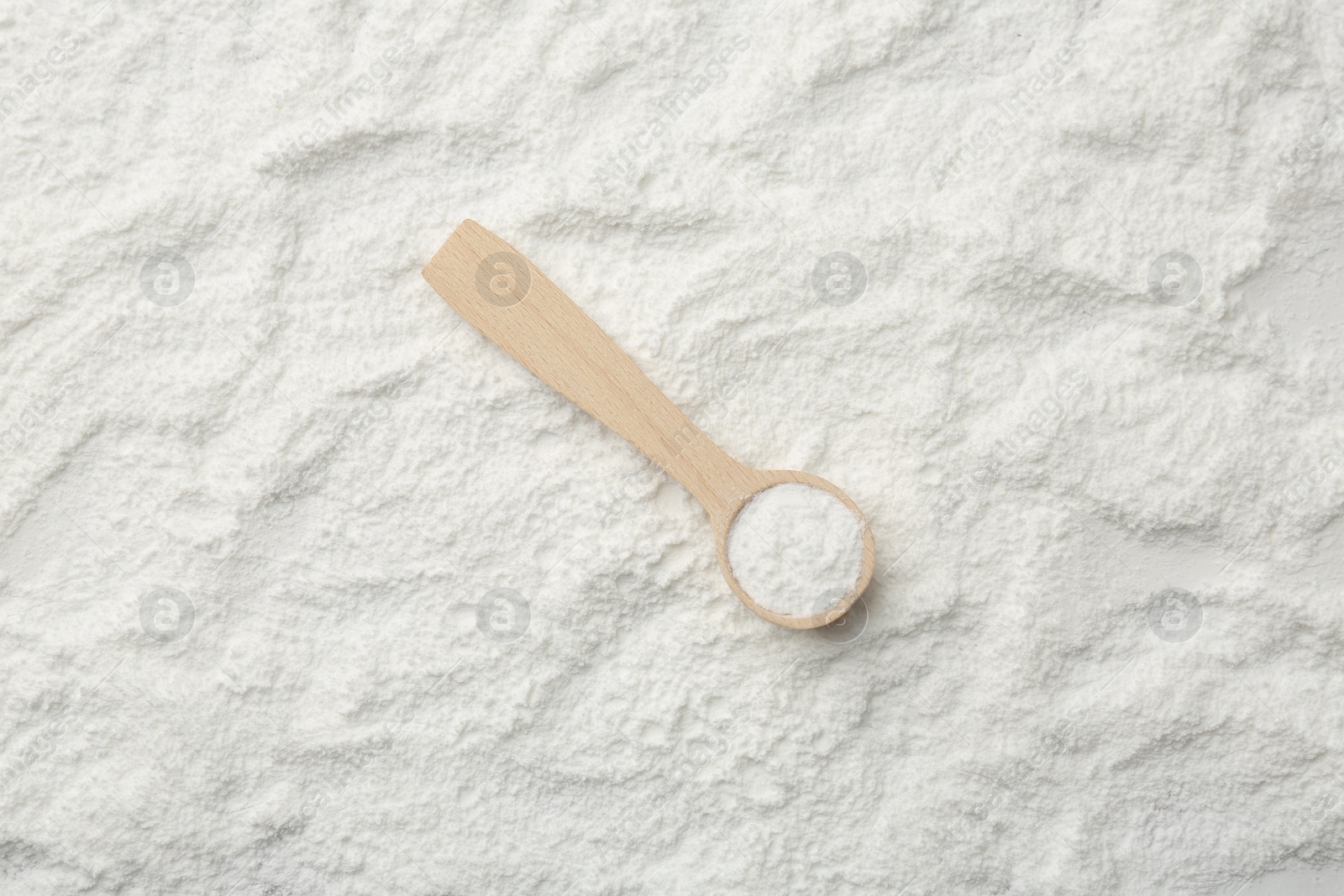 Photo of One wooden spoon on baking powder, top view