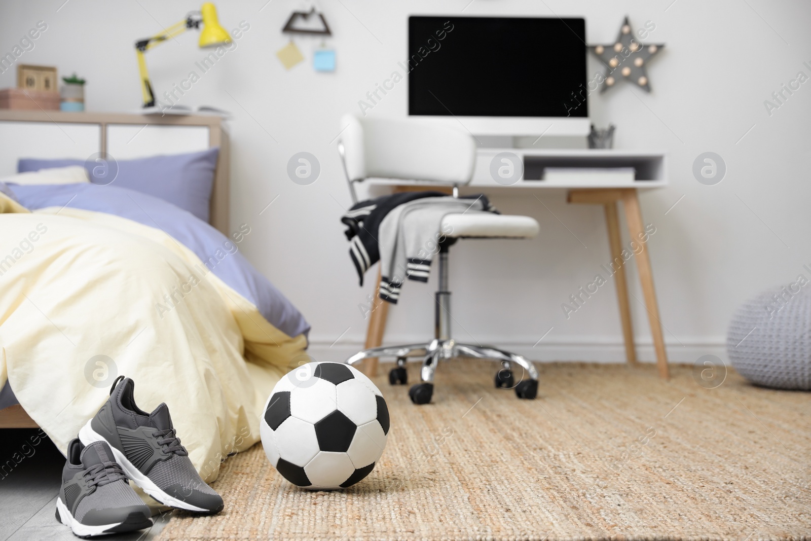 Photo of Soccer ball and sneakers near bed in teenager's room interior