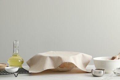 Photo of Cooking grissini. Bowl covered with towel and different ingredients on white wooden table