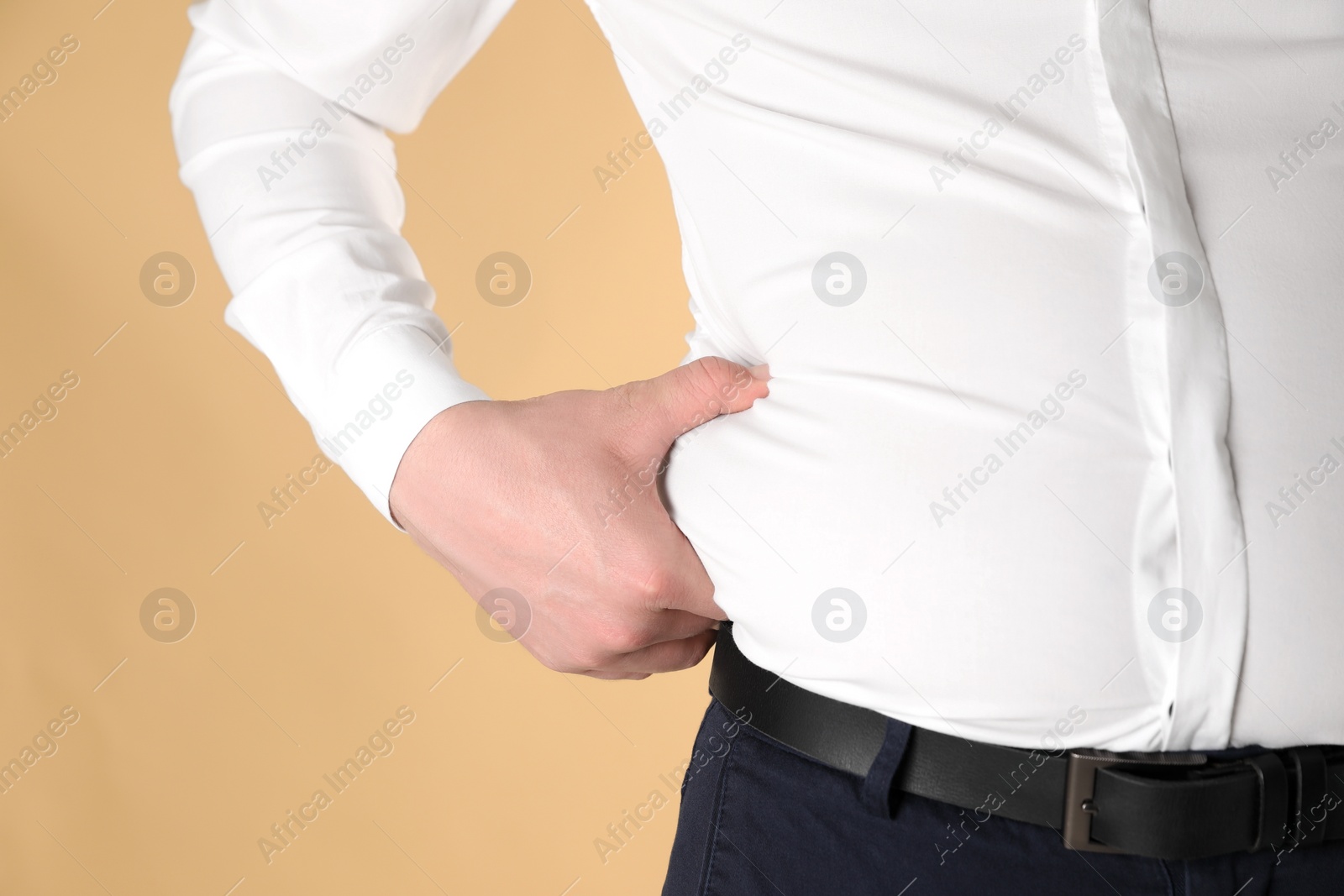 Photo of Overweight man in tight shirt on yellow background, closeup. Space for text