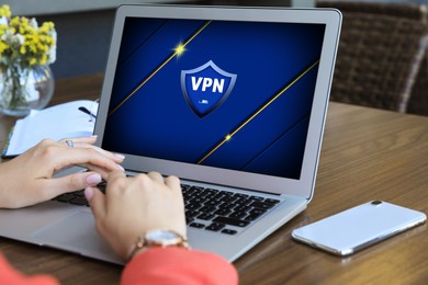 Image of Woman using laptop with switched on VPN at wooden table, closeup
