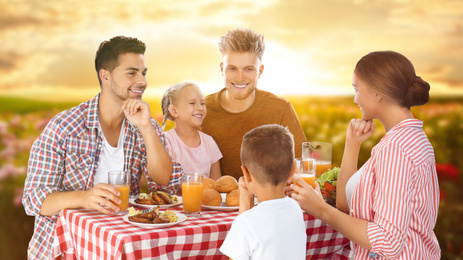 Image of Happy family having picnic at table in garden
