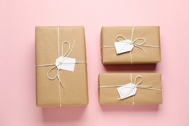 Parcels wrapped in kraft paper with tags on pink background, flat lay