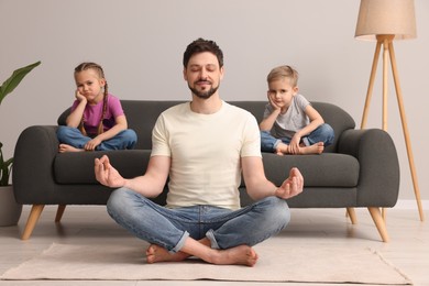 Photo of Father meditating while his children getting bored at home