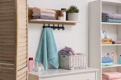 Fresh towels, houseplant and toiletries on shelf in bathroom