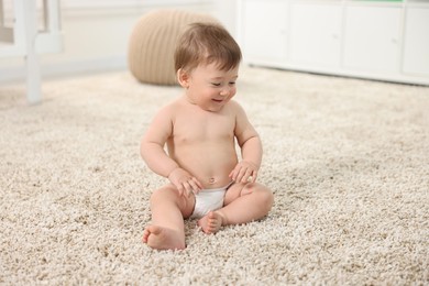 Cute baby boy sitting on carpet at home