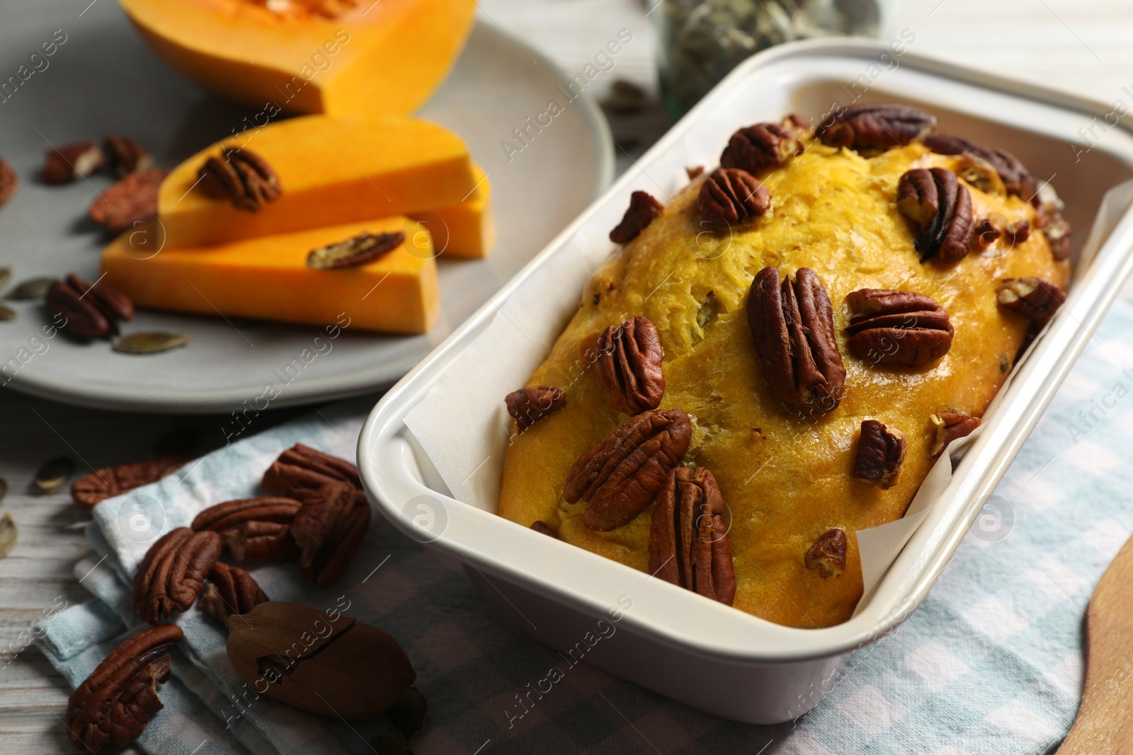 Photo of Delicious pumpkin bread with pecan nuts on light wooden table