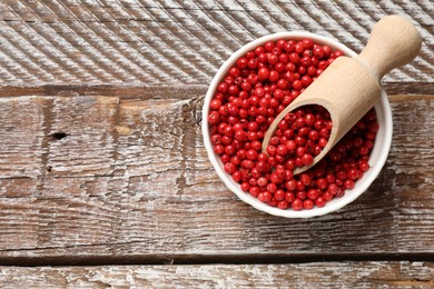 Photo of Aromatic spice. Red pepper in bowl and scoop on wooden table, top view. Space for text