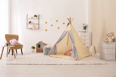 Photo of Cozy kids room interior with play tent and toys