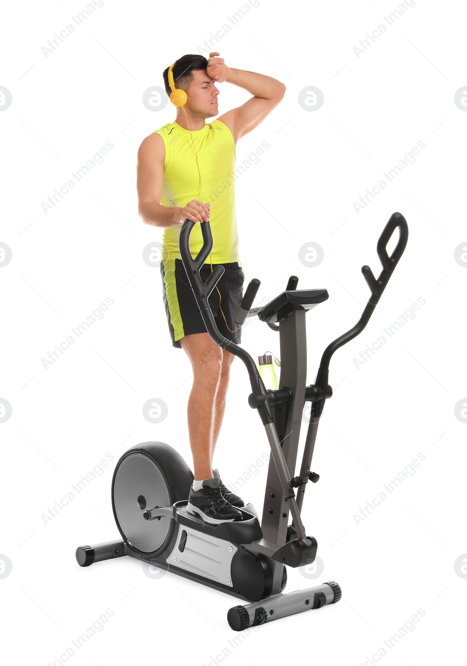 Photo of Tired man after training on modern elliptical machine against white background