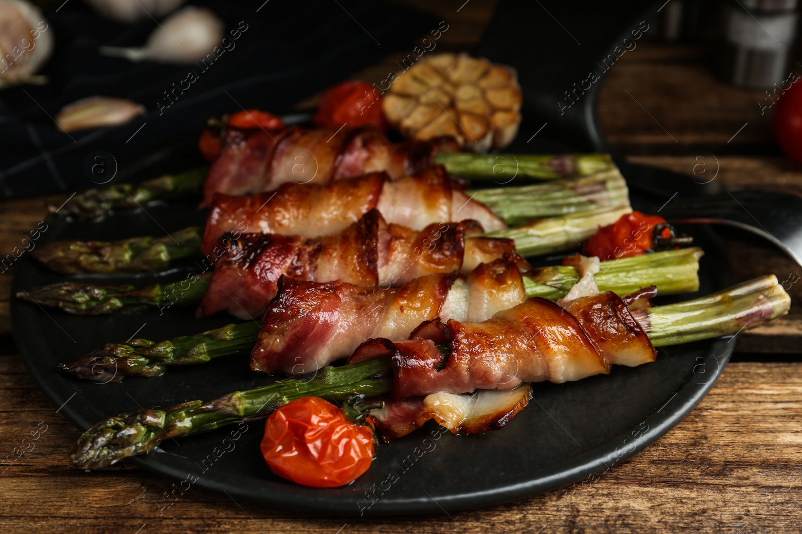 Photo of Oven baked asparagus wrapped with bacon on wooden table