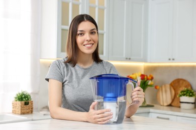 Woman with filter jug of water in kitchen