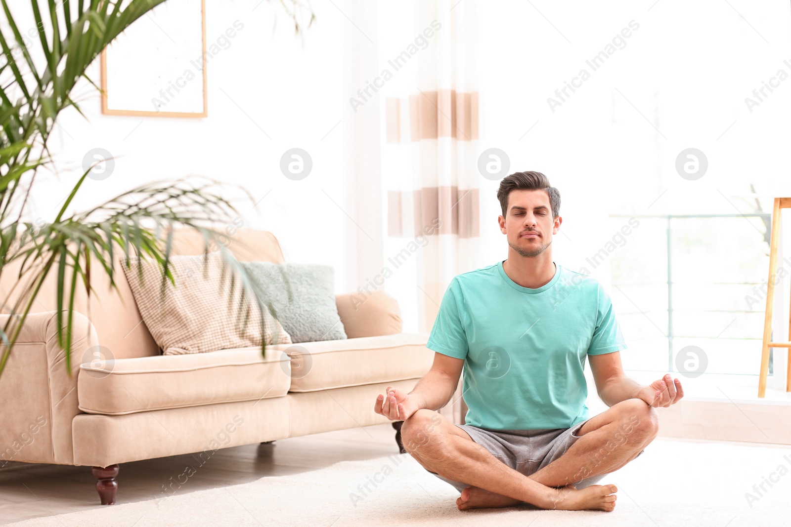 Photo of Man meditating on floor in living room, space for text. Zen concept