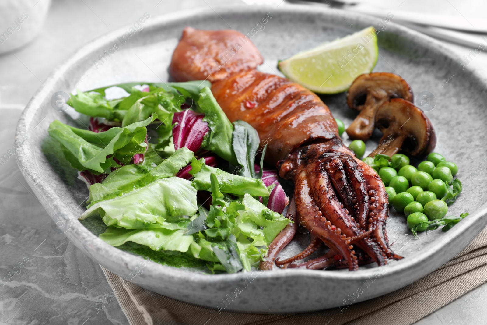 Photo of Tasty grilled squid served on white marble table, closeup