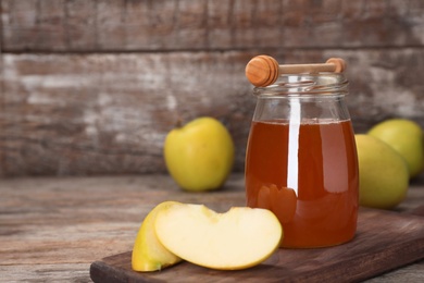 Photo of Jar of honey, apples and dipper on wooden table