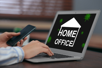 Woman with smartphone working on laptop at table, closeup. Home office