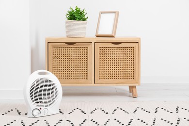 Photo of Electric fan heater on floor at home. Space for text