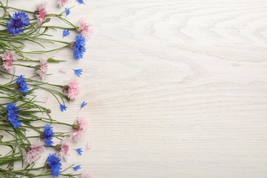 Beautiful bright cornflowers on white wooden background, flat lay. Space for text