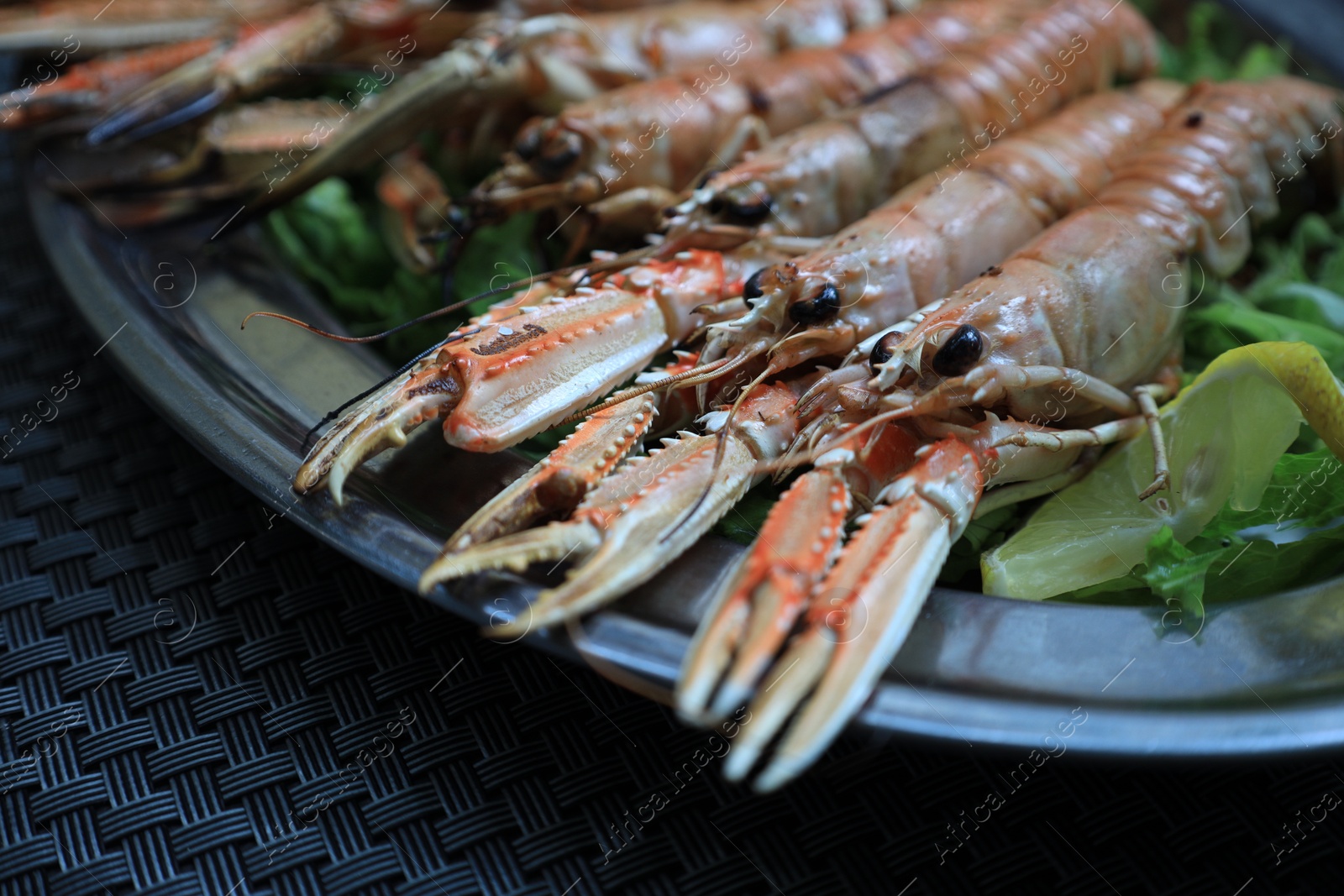 Photo of Plate with tasty boiled crayfish and salad on black table, closeup