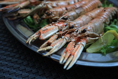 Photo of Plate with tasty boiled crayfish and salad on black table, closeup