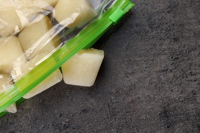 Photo of Frozen cauliflower puree cubes in plastic bag on grey table, top view. Space for text