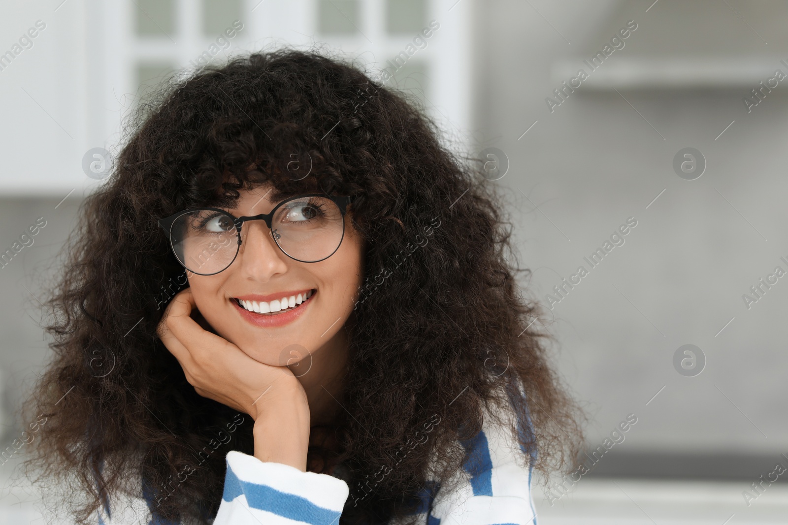 Photo of Portrait of beautiful woman with curly hair indoors. Attractive lady smiling and posing for camera. Space for text