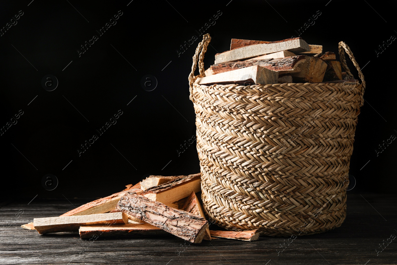 Photo of Cut firewood on table against black background