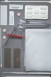 Photo of Sterile gynecological examination kit and medicaments on grey background, flat lay