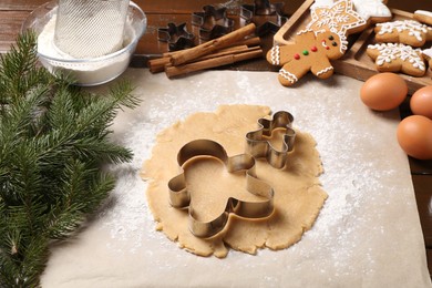 Photo of Christmas composition with raw dough and cookie cutters on wooden table