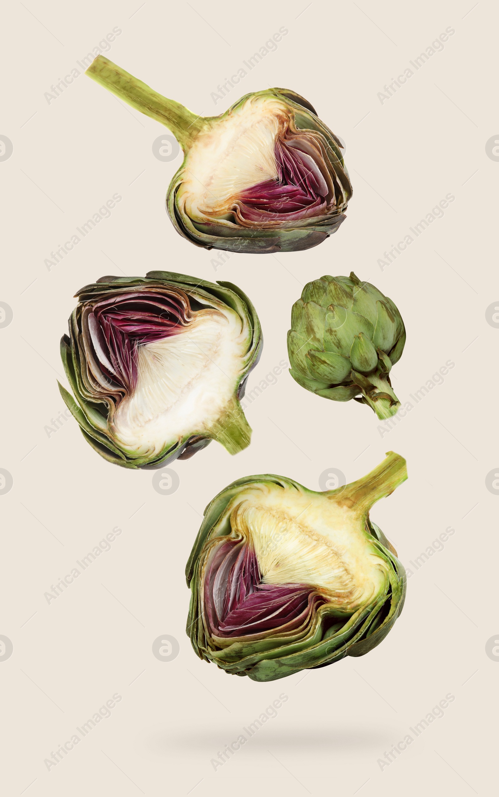 Image of Fresh raw artichokes falling on light grey background