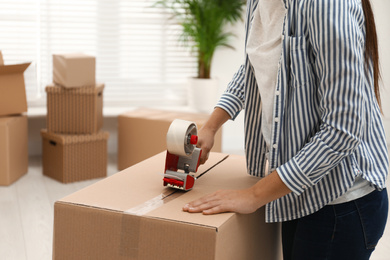 Photo of Woman packing cardboard box indoors, closeup. Moving day