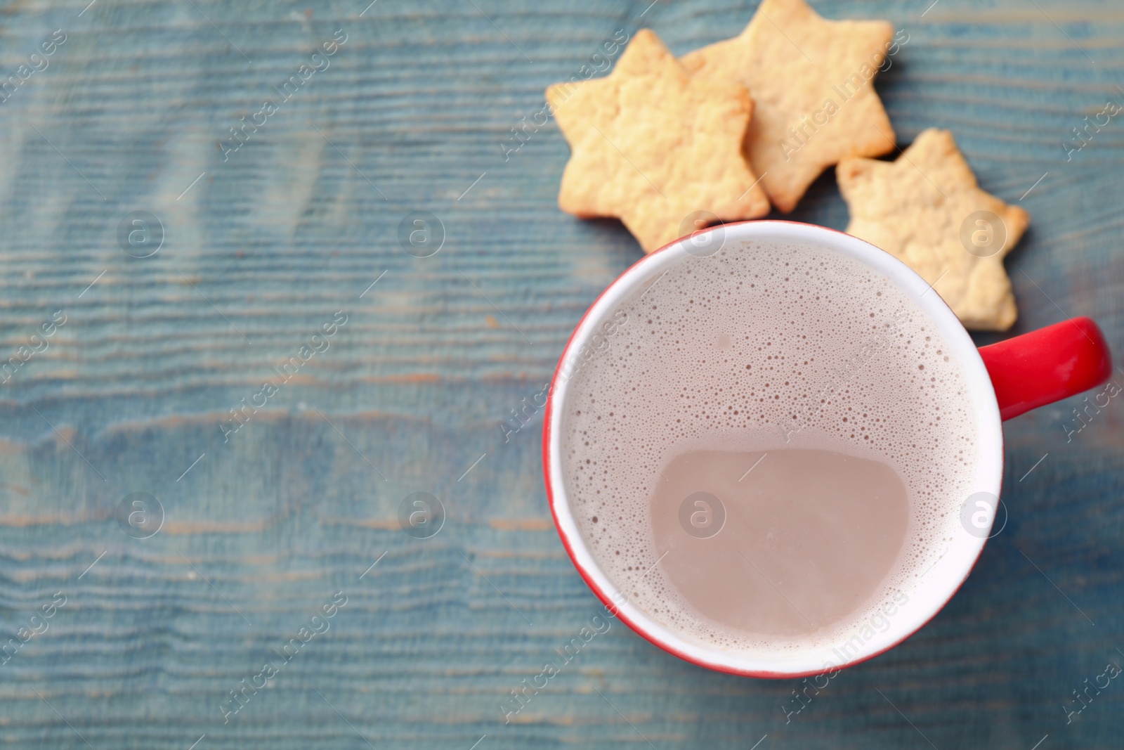 Photo of Cup of tasty cocoa and cookies on blue wooden table, top view. Space for text