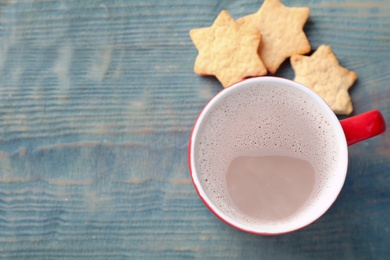 Photo of Cup of tasty cocoa and cookies on blue wooden table, top view. Space for text