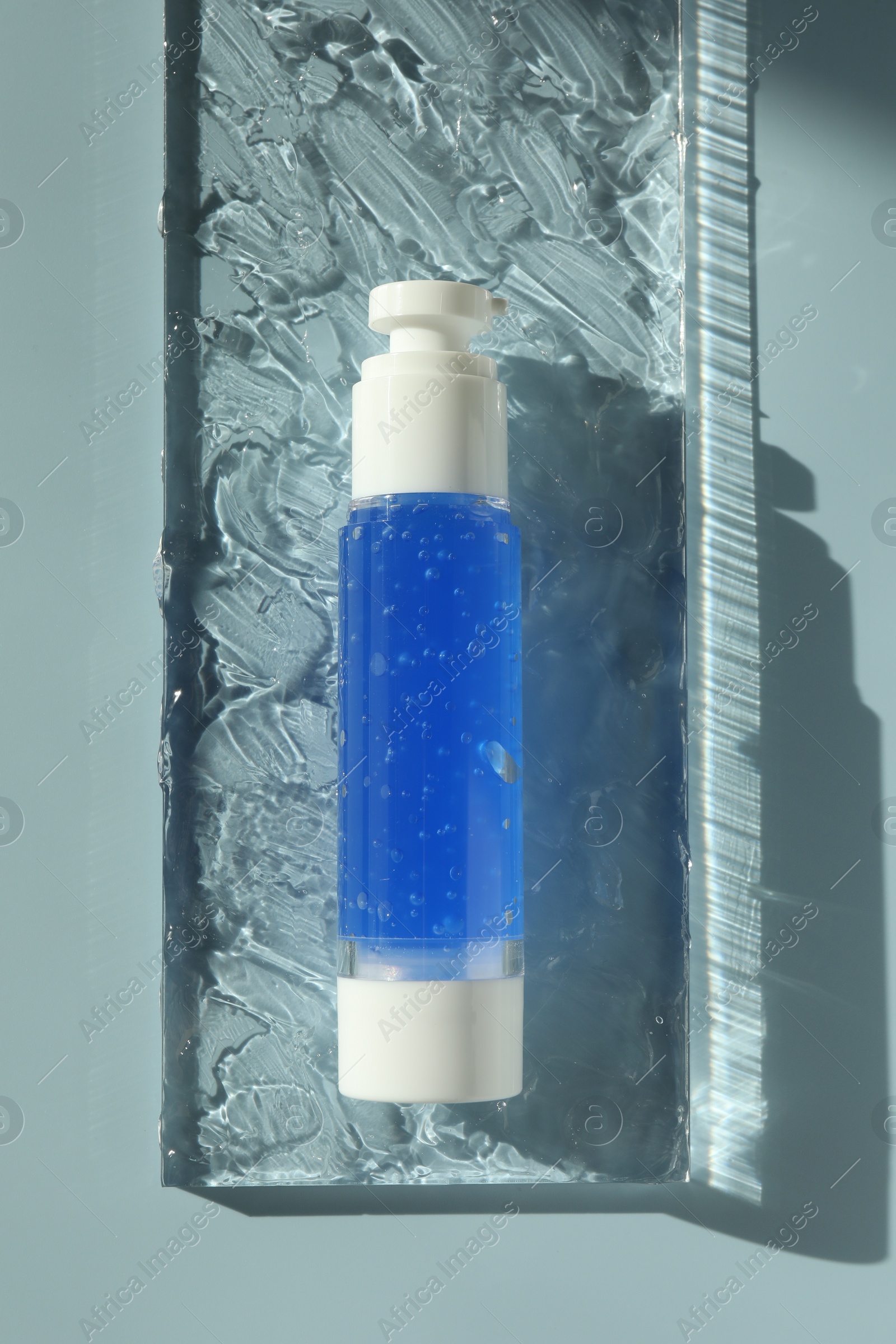 Photo of Bottle of cosmetic product on light blue background, top view